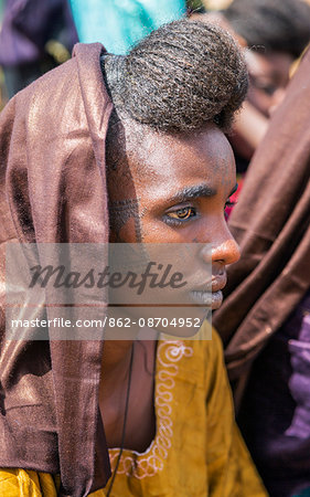 Niger, Agadez, Inebeizguine. A Wodaabe girl with traditional facial scarification watches a Gerewol ceremony performed by the young men of her tribe.