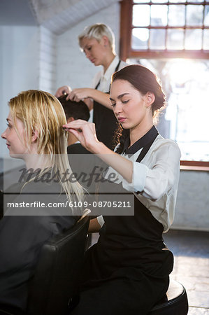 Hairstylist combing client hair in salon