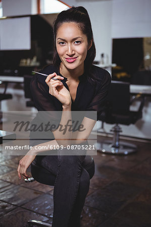 Portrait of smiling female hairdresser holding scissor in hair salon