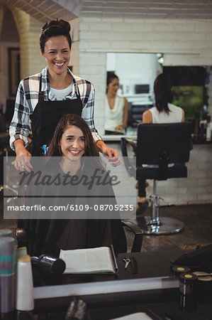 Smiling female hairdresser working on the client in hair salon