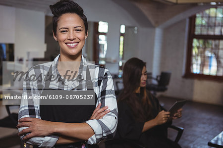 Portrait of female hairdresser standing with arm crossed at a salon