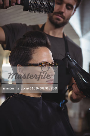 woman getting her hair dried with the hair dryer in hair salon