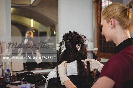 Female hairdresser dyeing hair of her client in salon
