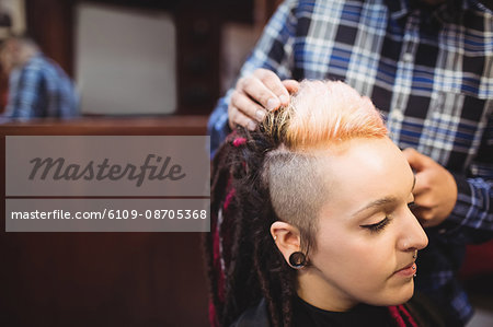 Woman getting her hair trimmed with trimmer in barber shop