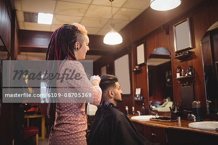 Female barber styling customer hair in barber shop