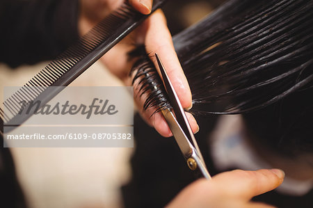 Man getting his hair trimmed with scissor in barber shop