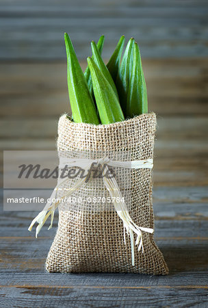 A heap of raw okra or Lady's fingers or gumbo in a bag on wooden background