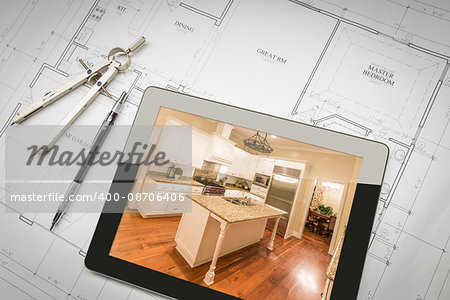 Computer Tablet Showing Finished Kitchen Sitting On House Plans With Pencil and Compass.