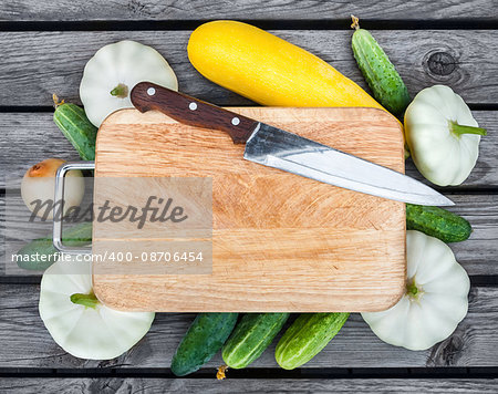 Cutting board, knife, fresh vegetables on wooden table.  Top view with copy space.
