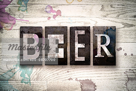 The word "BEER" written in vintage dirty metal letterpress type on a whitewashed wooden background with ink and paint stains.