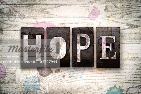 The word "HOPE" written in vintage dirty metal letterpress type on a whitewashed wooden background with ink and paint stains.