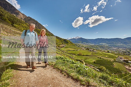 Mature couple hiking along country road, Meran, South Tyrol, Italy