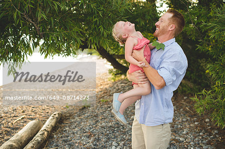 Mid adult man carrying and tickling daughter at Lake Ontario, Oshawa, Canada