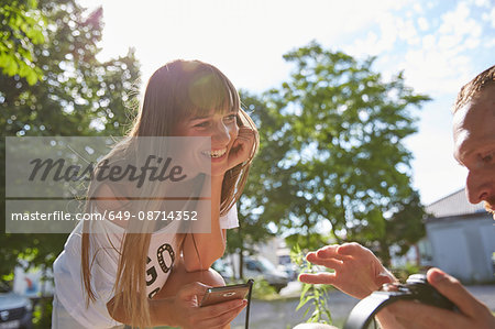 Young couple outdoors, listening to music through earphones