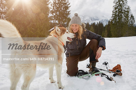 Mature woman crouching by beside dog in snowy landscape, Elmau, Bavaria, Germany