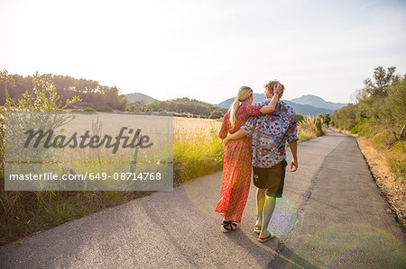 Rear view of romantic young couple strolling along rural road, Majorca, Spain