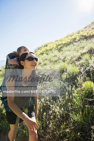 Mother carrying young daughter on back, hiking the Bonneville Shoreline Trail in the Wasatch Foothills above Salt Lake City, Utah, USA