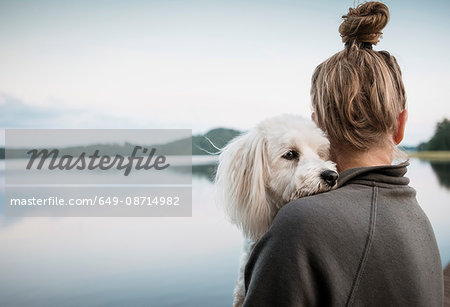 Coton de tulear dog looking over woman's shoulder at lake, Orivesi, Finland