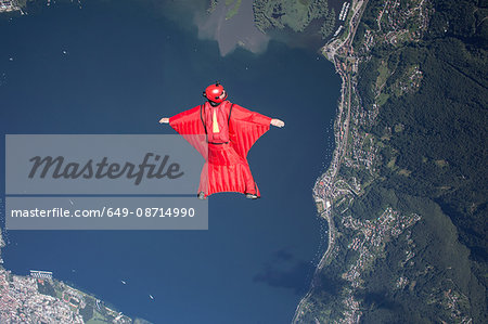 Wingsuit skydiver pilot flying over lake, Locarno, Tessin, Switzerland