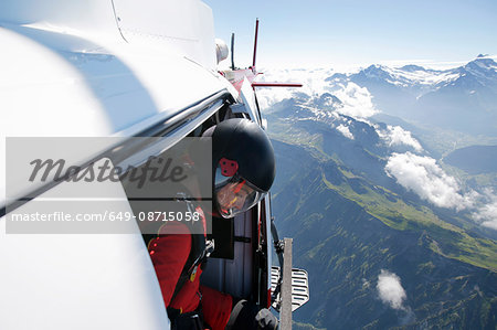 Female sky diver in helicopter checking for exit over mountain, Interlaken, Berne, Switzerland