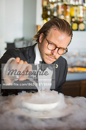 Denmark, Hillerod, Copenhagen. A barman prepares a cocktail at Hotel D'Angleterre using liquid nitrogen. .