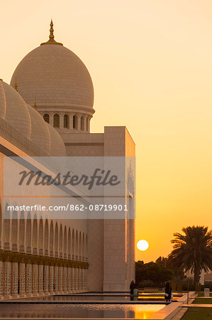 United Arab Emirates, Abu Dhabi. The white marble exterior and water pools of Sheikh Zayed Grand Mosque at sunset.