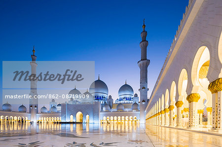 United Arab Emirates, Abu Dhabi. The courtyard and white marble exterior of Sheikh Zayed Grand Mosque. The spectacular evening lighting varies from white to blue according to the phases of the moon.