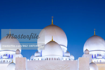 United Arab Emirates, Abu Dhabi. The white marble domes of Sheikh Zayed Grand Mosque. The main dome pictured is 85m high and comparable in size to St Paul's Cathedral. The spectacular evening lighting varies from white to blue according to the phases of the moon.