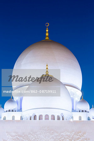 United Arab Emirates, Abu Dhabi. The white marble domes of Sheikh Zayed Grand Mosque. The main dome pictured is 85m high and comparable in size to St Paul's Cathedral. The spectacular evening lighting varies from white to blue according to the phases of the moon.