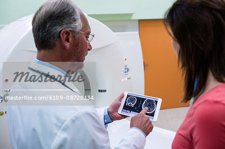 Doctor explaining to patient about brain mri scans on tablet at hospital