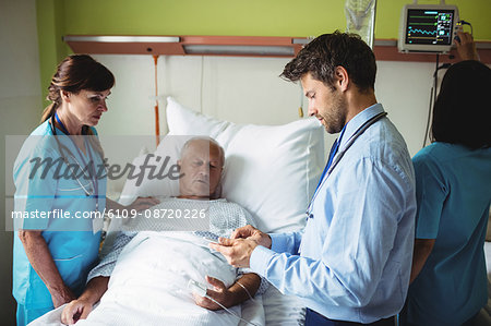 Male doctor showing report to senior patient on digital tablet in hospital