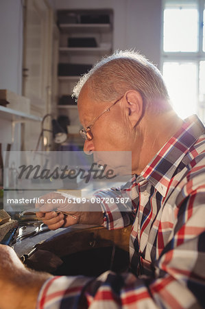 Attentive goldsmith using hand piece machine in workshop