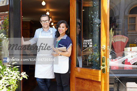 Portrait of male and female workers in bakery, standing in doorway