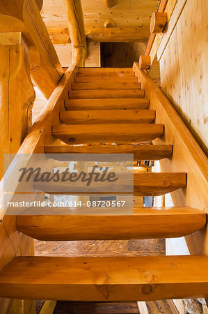 Wooden stairs leading upstairs in handcrafted red cedar log home, Quebec, Canada