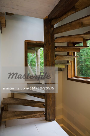 Cherrywood spiraling staircase around pinewood post in cottage style log home, Quebec, Canada