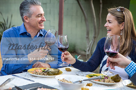 Mature friends making a red wine toast at garden party table