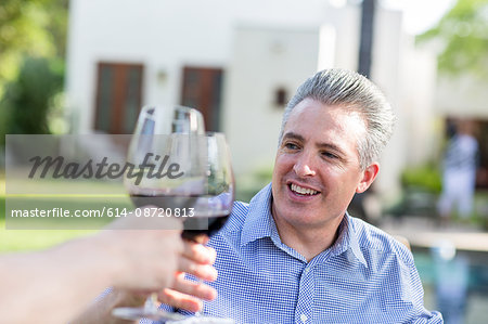 Mature couple making a red wine toast in garden