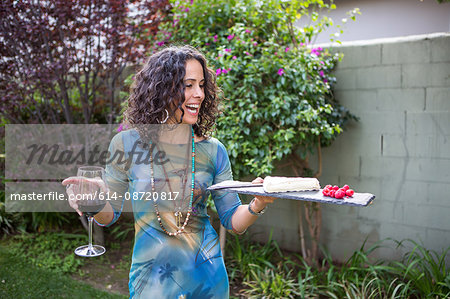 Mature woman holding cutting board and red wine at garden party