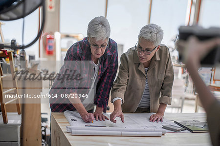 Female carpenters discussing blueprint in furniture making workshop