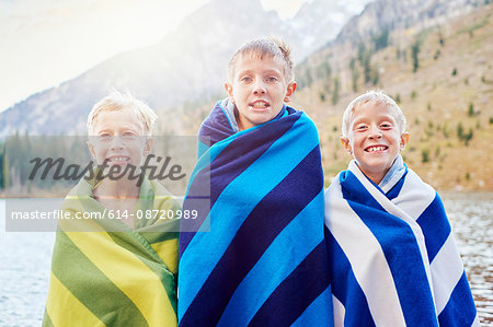 Portrait of male twins and brother wrapped in blankets, shivering, Grand Teton National Park, Wyoming, USA