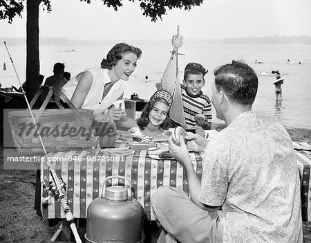 1950s FAMILY MOTHER FATHER BOY GIRL EATING PICNIC LAKESIDE PICNIC TABLE