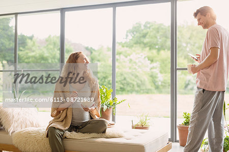 Pregnant couple eating cereal and drinking coffee in living room