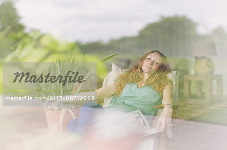 Comfortable woman relaxing in armchair at living room window