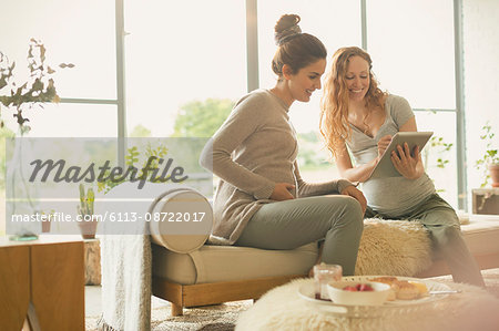 Pregnant women using digital tablet in living room