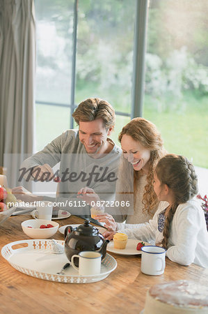 Family eating cupcakes and fruit at dining table