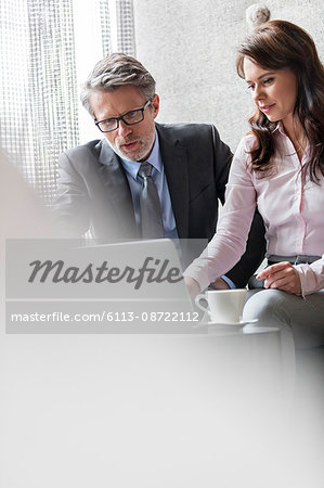 Businessman and businesswoman using laptop