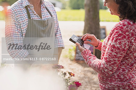 Plant nursery worker waiting as woman uses credit card machine