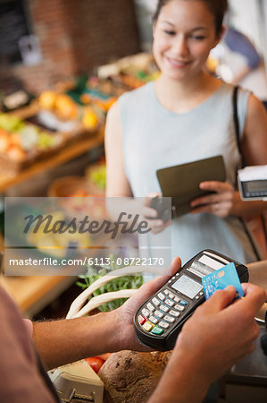 Woman watching grocery store clerk using credit card machine