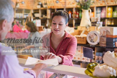 Woman sampling cheese at deli counter in market