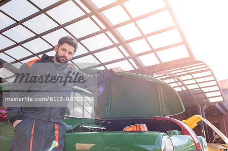 Portrait confident mechanic fixing classic car in auto repair shop